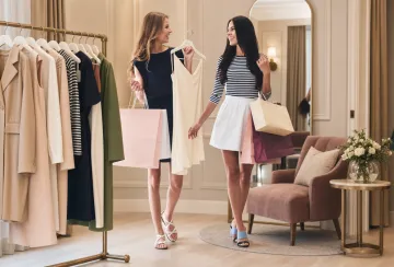 Personal shopper assisting client with curated clothing selection in boutique