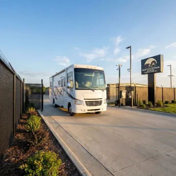 Large motorhome stored in secure fenced outdoor storage area with paved access