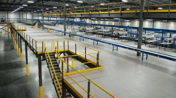 Freestanding structural steel warehouse mezzanine with open column spans and conveyor integration