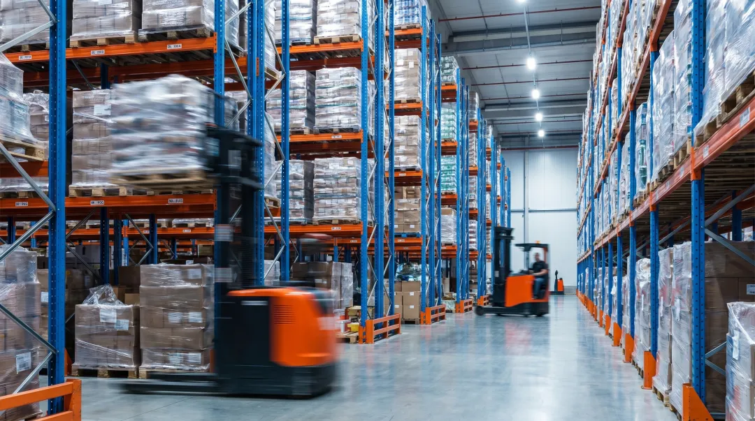 High-traffic distribution center warehouse with structural pallet racking and forklifts operating