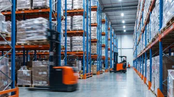 High-traffic distribution center warehouse with structural pallet racking and forklifts operating