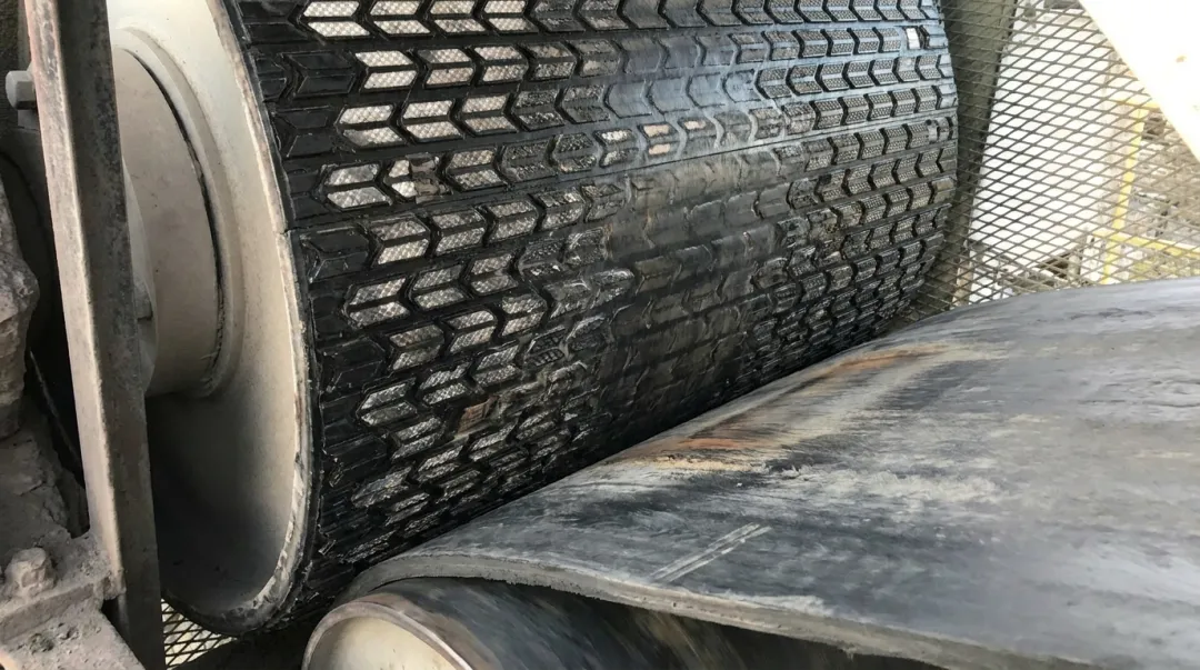 Conveyor belt slippage on drive pulley showing worn lagging and surface contact