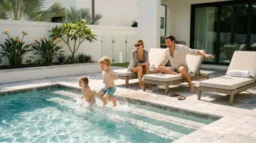 Happy family with young children enjoying a relaxed vacation day by a private swimming pool