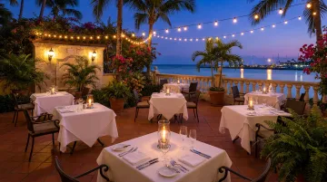 Upscale waterfront restaurant patio with candlelit tables and water views at night