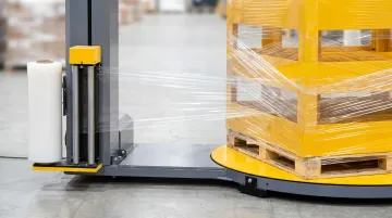 Powered pallet stretch wrap machine applying pre-stretched film to warehouse pallet