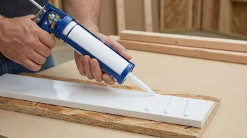PVC trim board being bonded to wooden framing with construction adhesive
