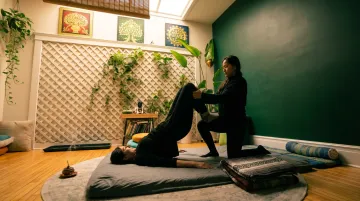 Thai bodywork practitioner performing assisted stretching therapy session
