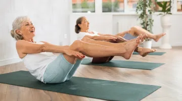 Active older woman practicing Pilates mat exercises in bright studio setting