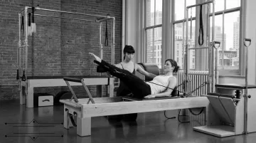 Classical Pilates instructor guiding client on Cadillac apparatus at The Pilates Room NYC