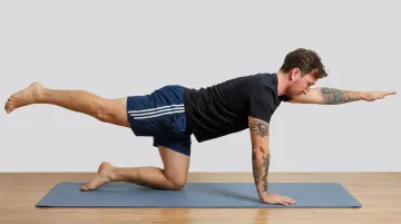 Person performing bird dog exercise on mat with opposite arm and leg extended