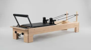 Pilates reformer machine showing spring resistance carriage foot bar and straps