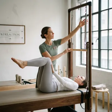 Instructor guiding Cadillac Pilates movement