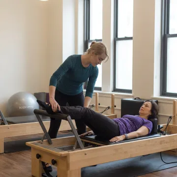 Instructor guiding beginner on Pilates equipment