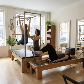 Pilates instructor guiding two clients on reformers