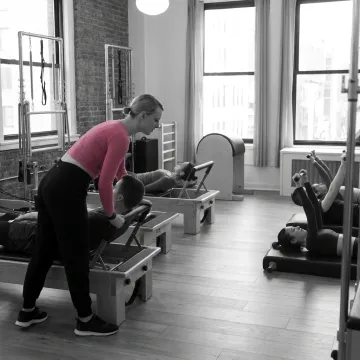 Instructor guiding Reformer Pilates students
