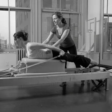 Instructor guiding a Pilates reformer session