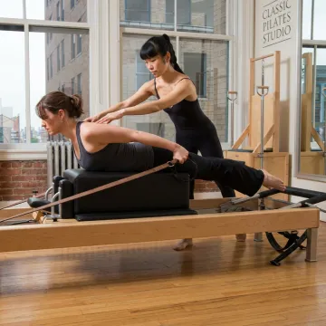 Pilates client training on a reformer in a boutique studio