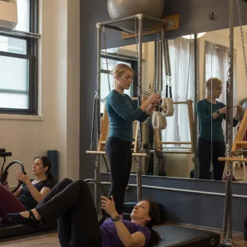 Instructor guiding Tower Pilates apparatus work