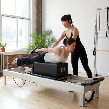 Instructor guiding a Pilates client on the Reformer