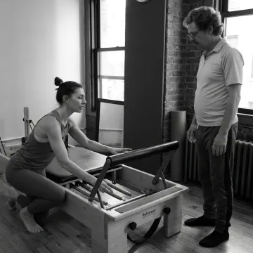 Instructor explaining Pilates reformer setup to a beginner