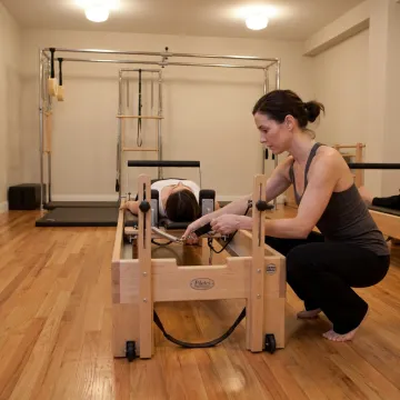 Instructor adjusting Pilates equipment for a client