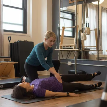 Pilates instructor correcting mat exercise form