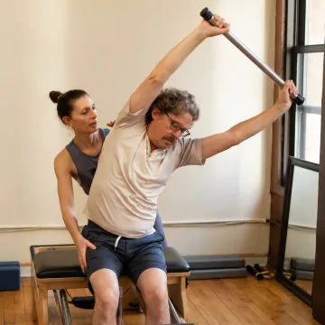 Beginner Pilates student on a reformer with instructor guidance