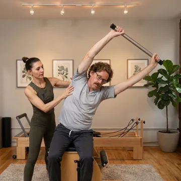 Pilates instructor assisting client on reformer