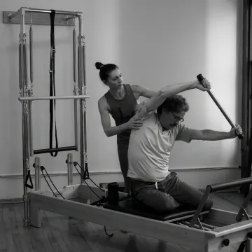 Pilates instructor guiding a beginner on equipment