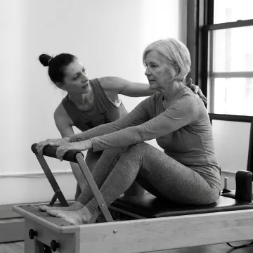 Instructor guiding senior through beginner Pilates