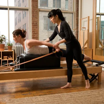 Pilates instructor assisting client on reformer