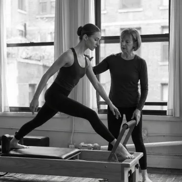 Dancer practicing Pilates on a reformer in a boutique studio