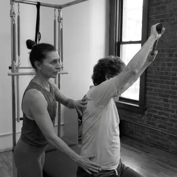 Pilates teacher guiding a private client through reformer exercises