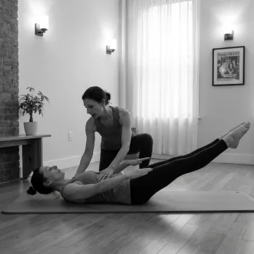 Instructor guiding a client through mat Pilates