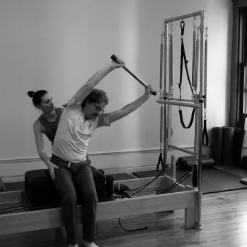 Pilates instructor guiding a client on a reformer