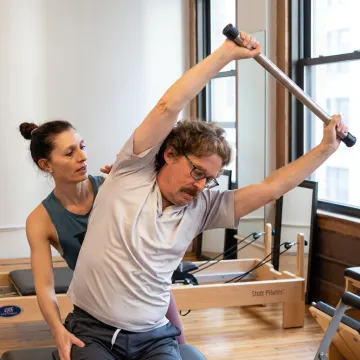 Instructor guiding a reformer Pilates session