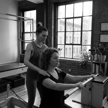 Instructor guiding a client on a Pilates reformer