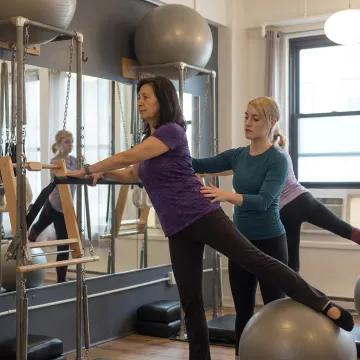 Instructor supervising bone-conscious Pilates strength training