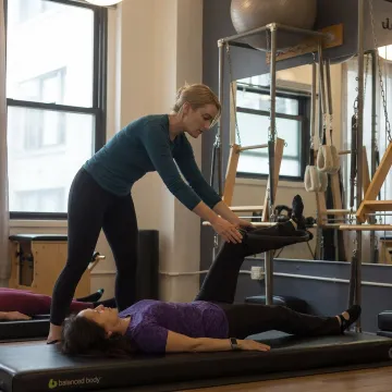 Instructor supporting gentle Pilates recovery work