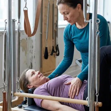 Instructor guiding postnatal Pilates core work