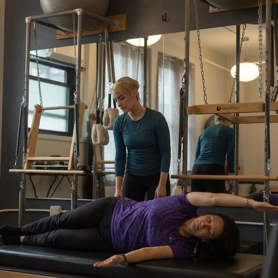 Instructor assessing Pilates movement on Cadillac apparatus