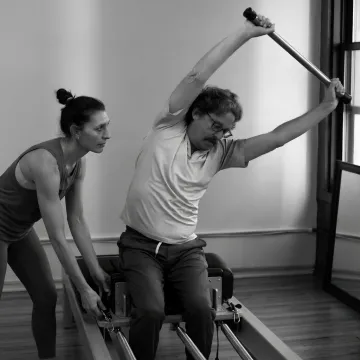 Pilates instructor adjusting a reformer during class