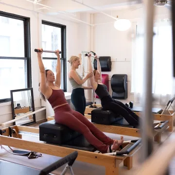 Instructor guiding small group Reformer strength training