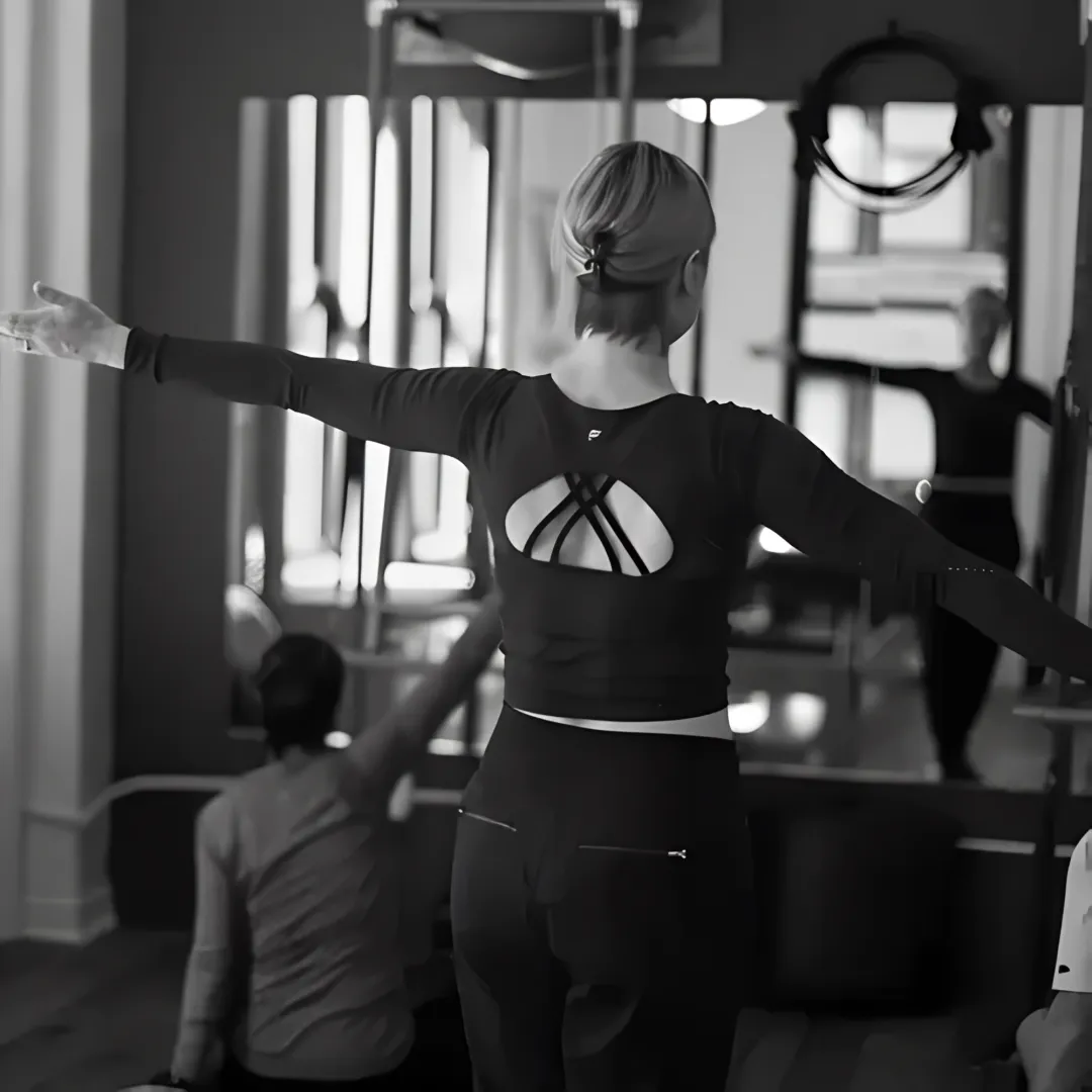 Pilates instructor adjusting client alignment during back pain session