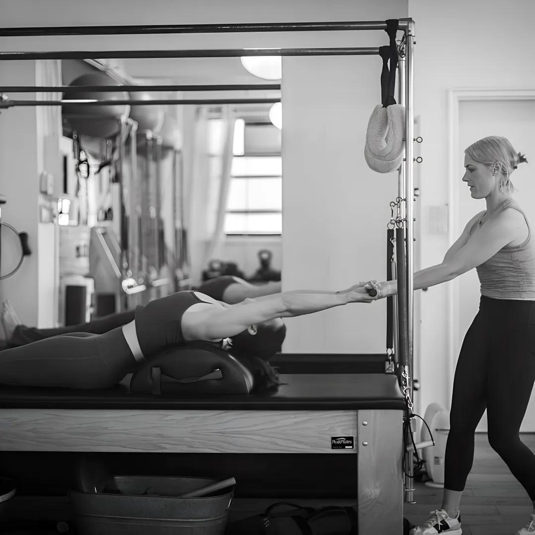 Pilates instructor adjusting a reformer during class