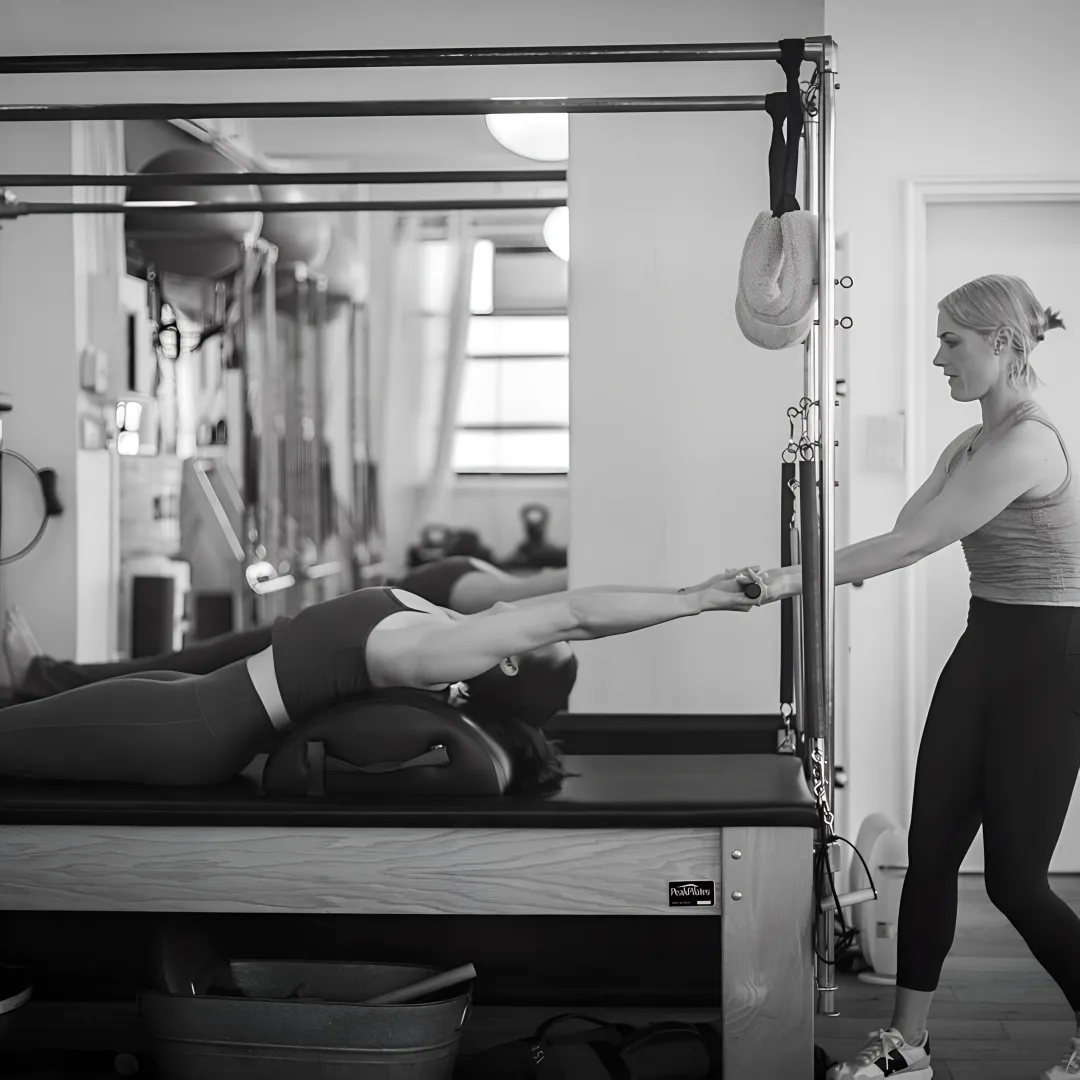Instructor guiding intermediate reformer Pilates technique