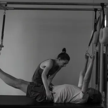 Instructor guiding a classical Pilates reformer session