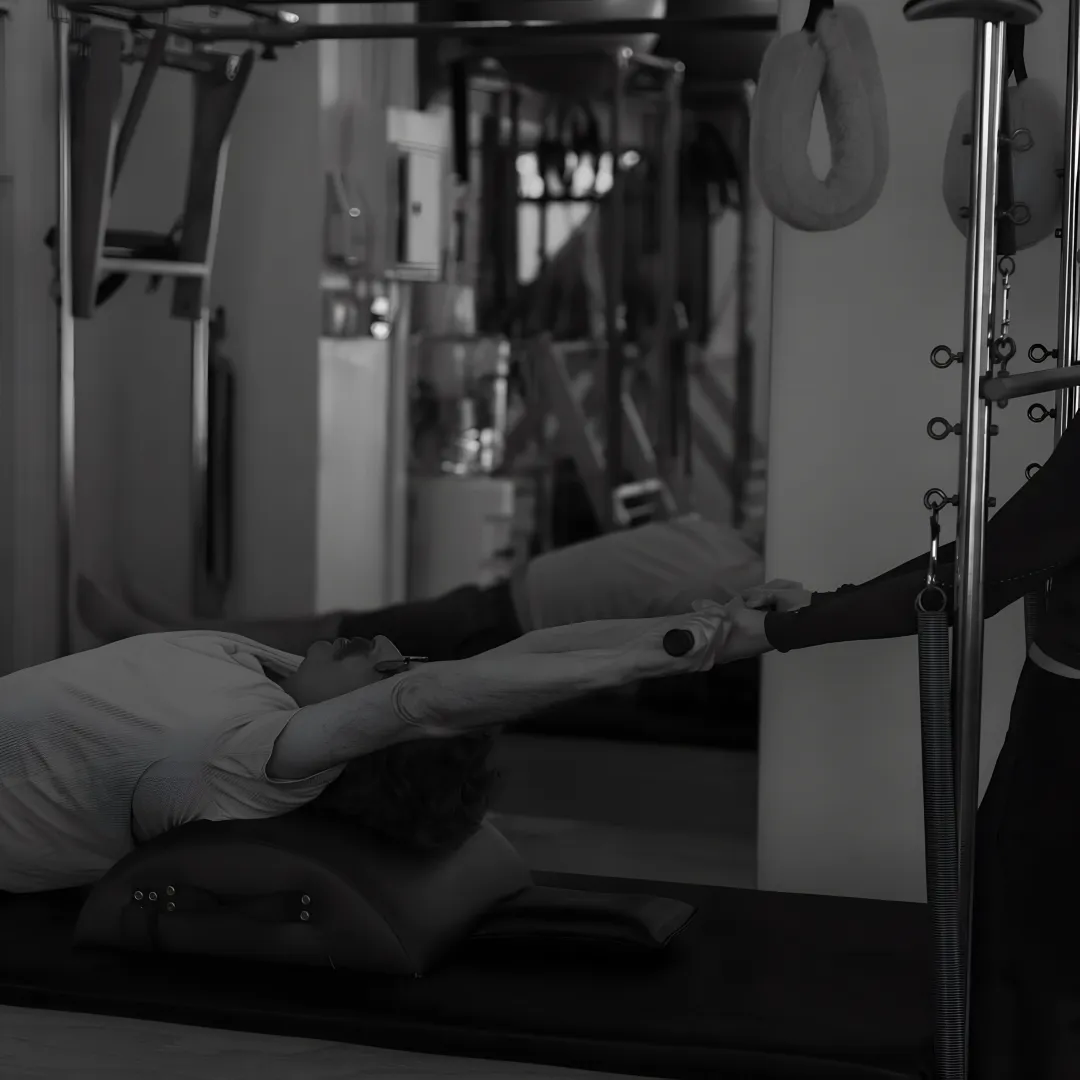 Instructor guiding a client on Pilates equipment