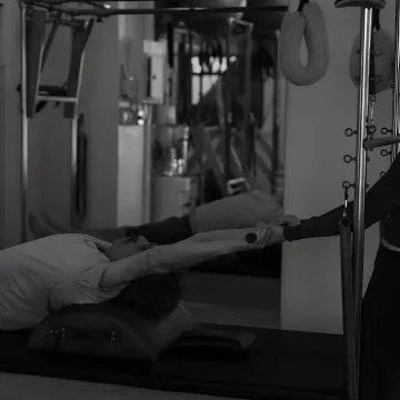 Instructor guiding a client on Pilates equipment