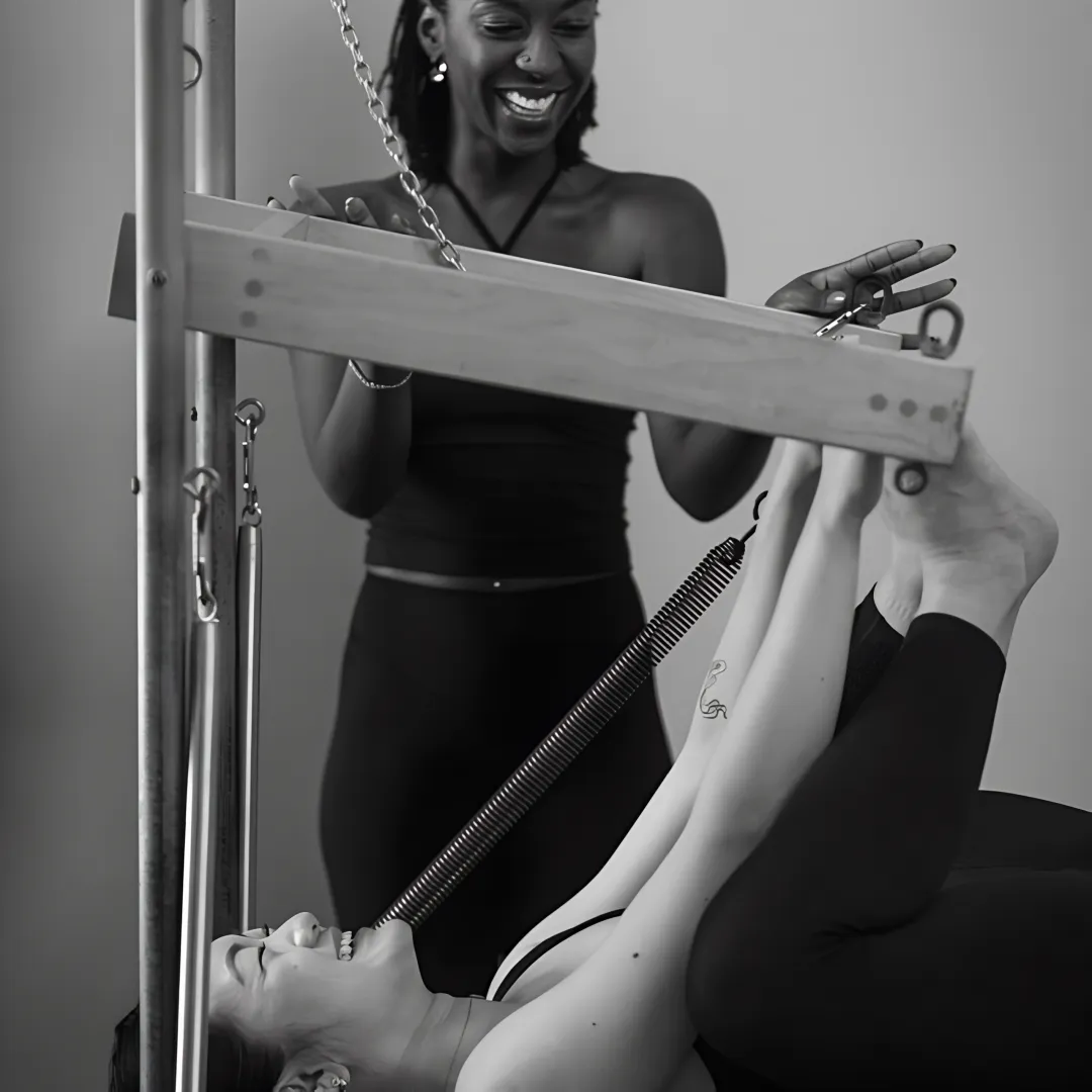 Pilates instructor guiding two clients on reformers